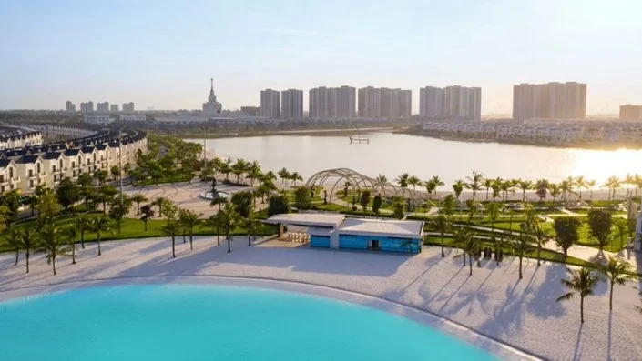 Toàn cảnh hồ nước mặn nhân tạo và bãi cát trắng, với các khu biệt thự và chung cư cao tầng phía xa