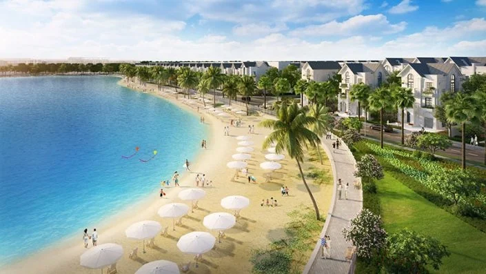 Bãi biển nhân tạo với cát trắng, hàng dù che và ghế nghỉ, cùng hàng dừa xanh mát và dãy nhà phố liền kề
