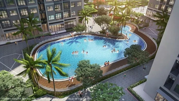 Toàn cảnh bể bơi nội khu hình uốn lượn với nhiều người đang bơi, bao quanh bởi cây xanh và các tòa nhà cao tầng
