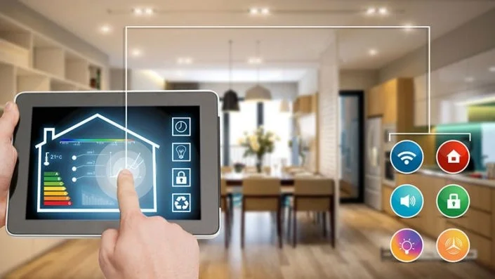 Bàn tay đang điều khiển hệ thống nhà thông minh Smart Home trên máy tính bảng, hiển thị các chức năng điều khiển ánh sáng, an ninh và nhiệt độ