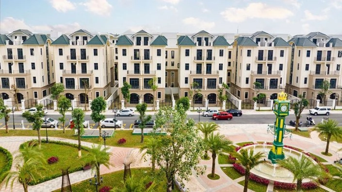 Quảng trường trung tâm với tháp đồng hồ, cây xanh và các dãy nhà phố liền kề kiến trúc tân cổ điển