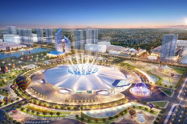 Phối cảnh tổng thể khu phức hợp thể thao và đô thị hiện đại vào ban đêm, nổi bật là sân vận động lớn được chiếu sáng rực rỡ và các tòa nhà cao tầng.