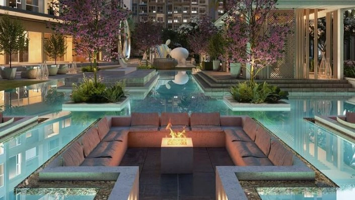 Khu vực lounge ngoài trời sang trọng với ghế sofa và hố lửa trung tâm giữa hồ bơi