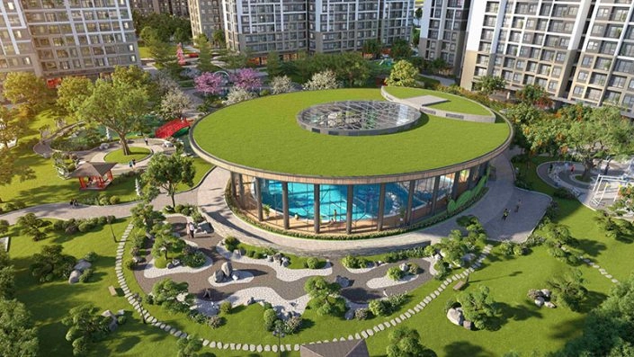 Toàn cảnh bể bơi bốn mùa trong nhà hình tròn với mái xanh và vườn Nhật Bản xung quanh