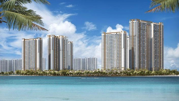 Các tòa nhà chung cư cao tầng nhìn từ mặt nước biển/hồ lớn với hàng cây xanh và bầu trời xanh